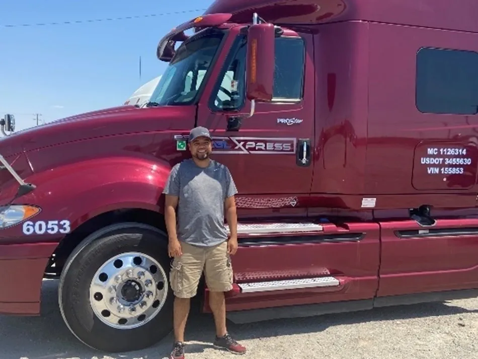 A man standing in front of a red truck.