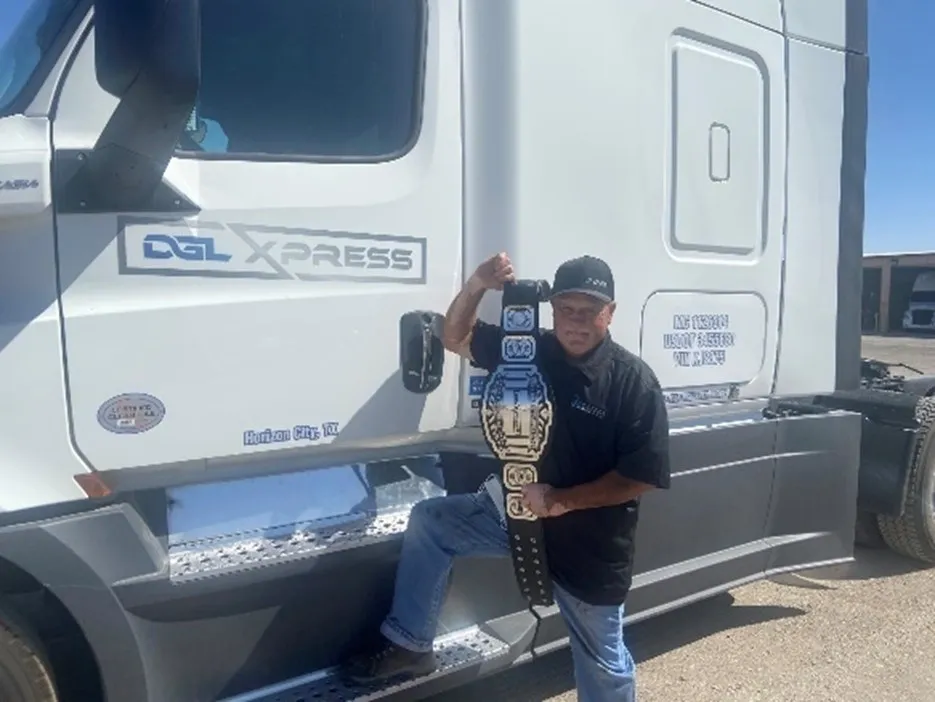 A man holding a trophy in front of a truck.